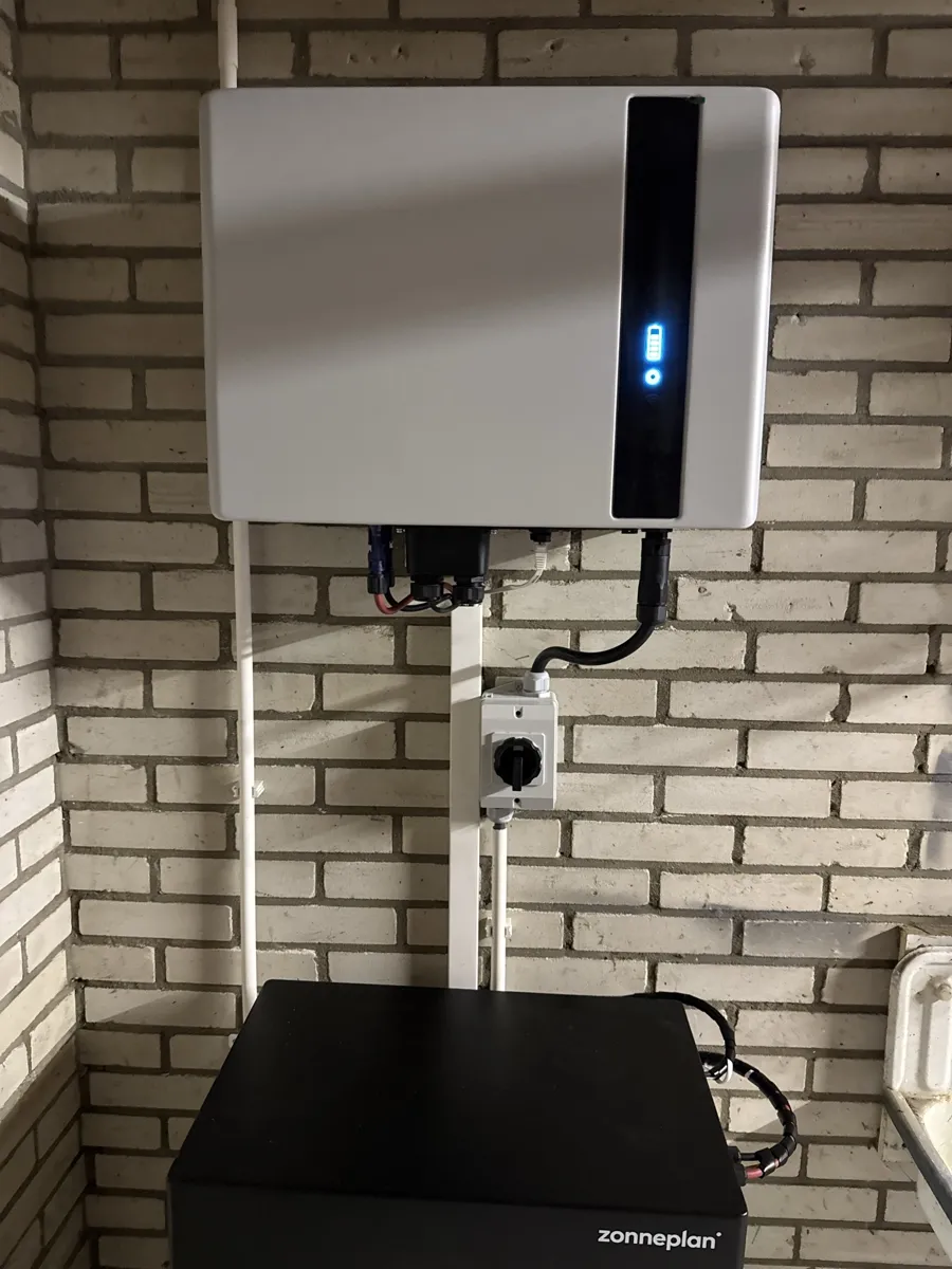 Omvormer met werkschakelaar boven de batterijmodules, vast aangesloten op een eigen groep